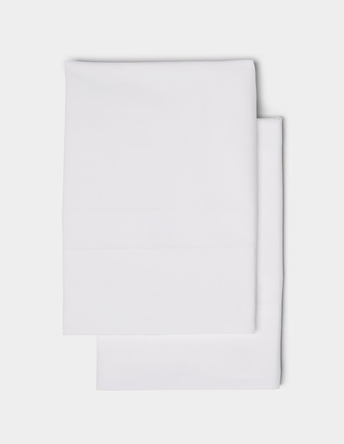 Two neatly folded Cozy Earth Soft-Wash Cotton Pillowcases are stacked on top of each other against a plain white background.|Color:White
