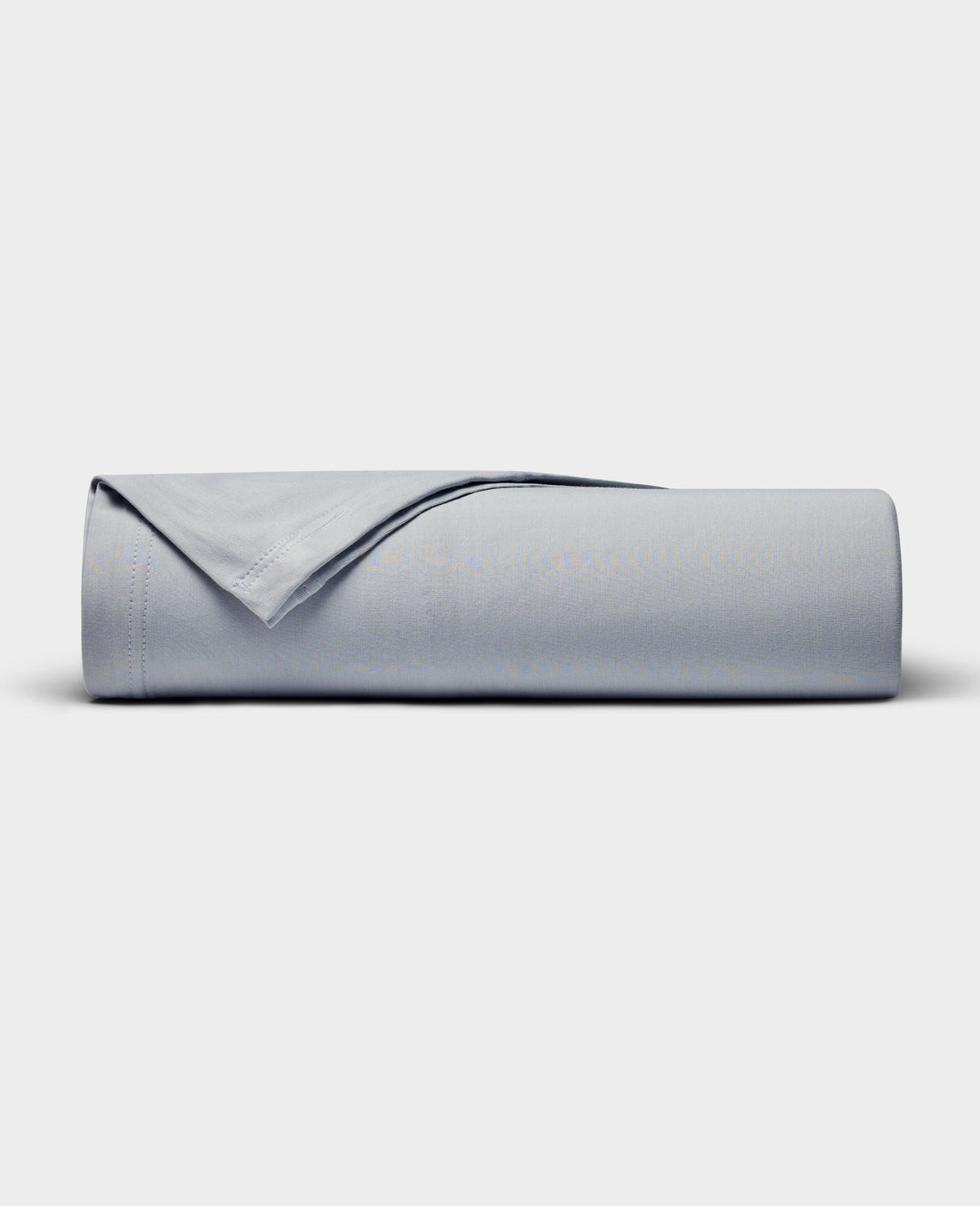 The Cozy Earth Bamboo Jersey Flat Sheet is neatly rolled with a folded edge and displayed on a plain white background.|Color:Shore