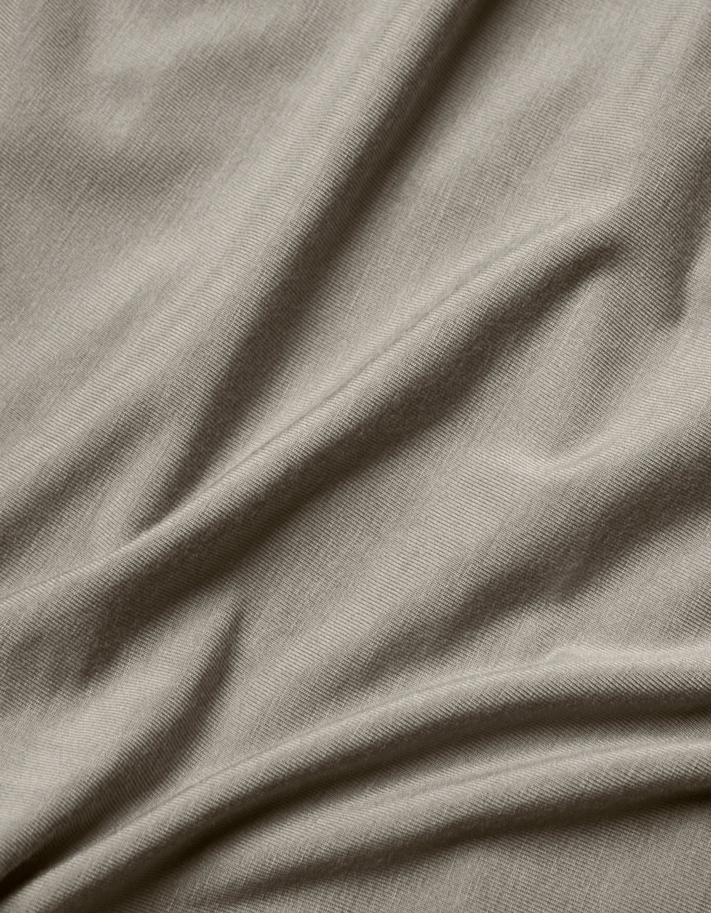 Close-up of the Cozy Earth Bamboo Jersey Flat Sheet in light grey, highlighting its smooth texture, subtle weave pattern, and soft folds.|Color:Stone