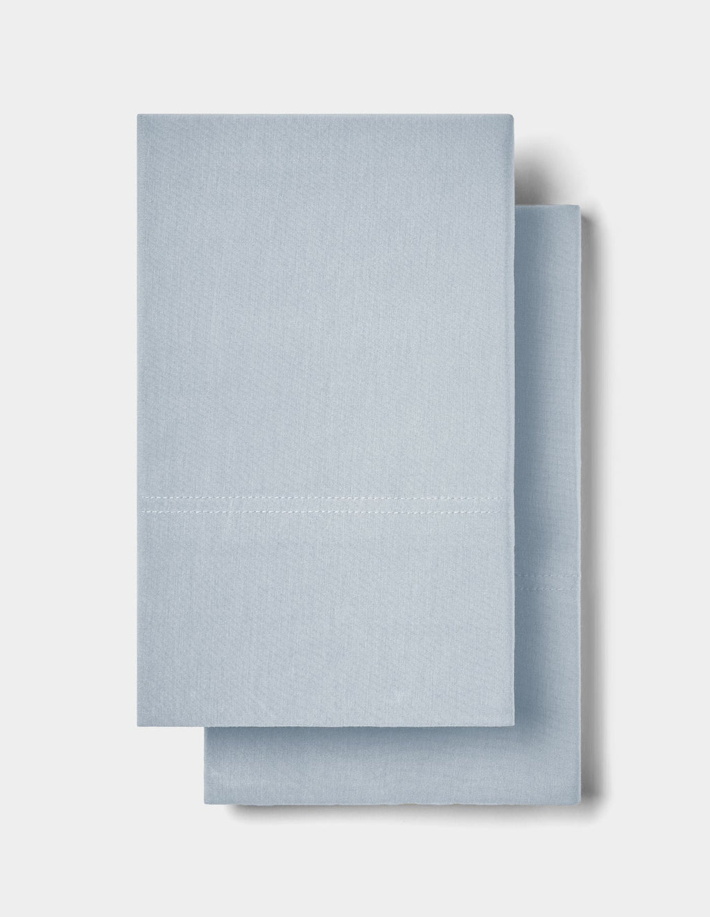 Two neatly folded Cozy Earth Bamboo Jersey Pillowcases in light blue are stacked on top of each other against a plain white background.|Color:Shore