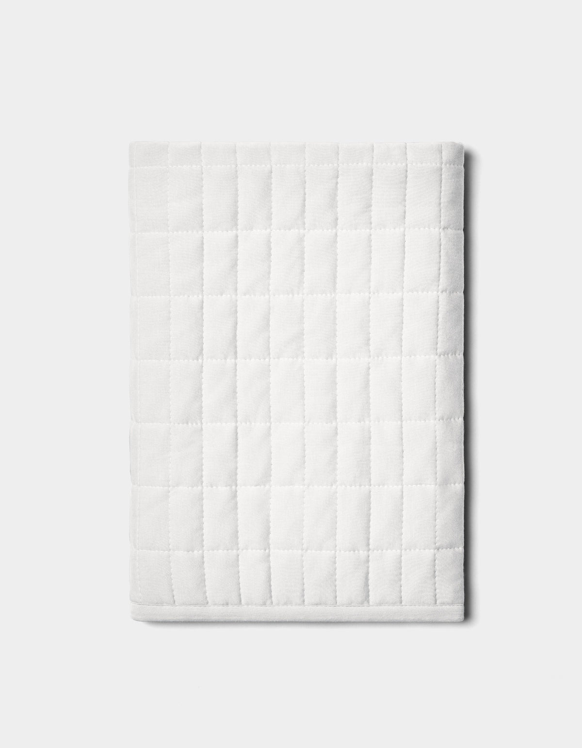 The Bamboo Jersey Quilted Shams by Cozy Earth are neatly folded with a square pattern and displayed on a plain light gray background.|Color:White