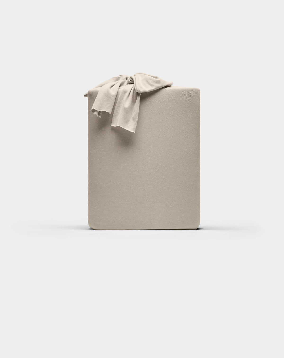 A neatly folded Cozy Earth Bamboo Jersey Sheet Set in beige, with a matching sheet draped over one corner, displayed against a plain white background.|Color:Driftwood