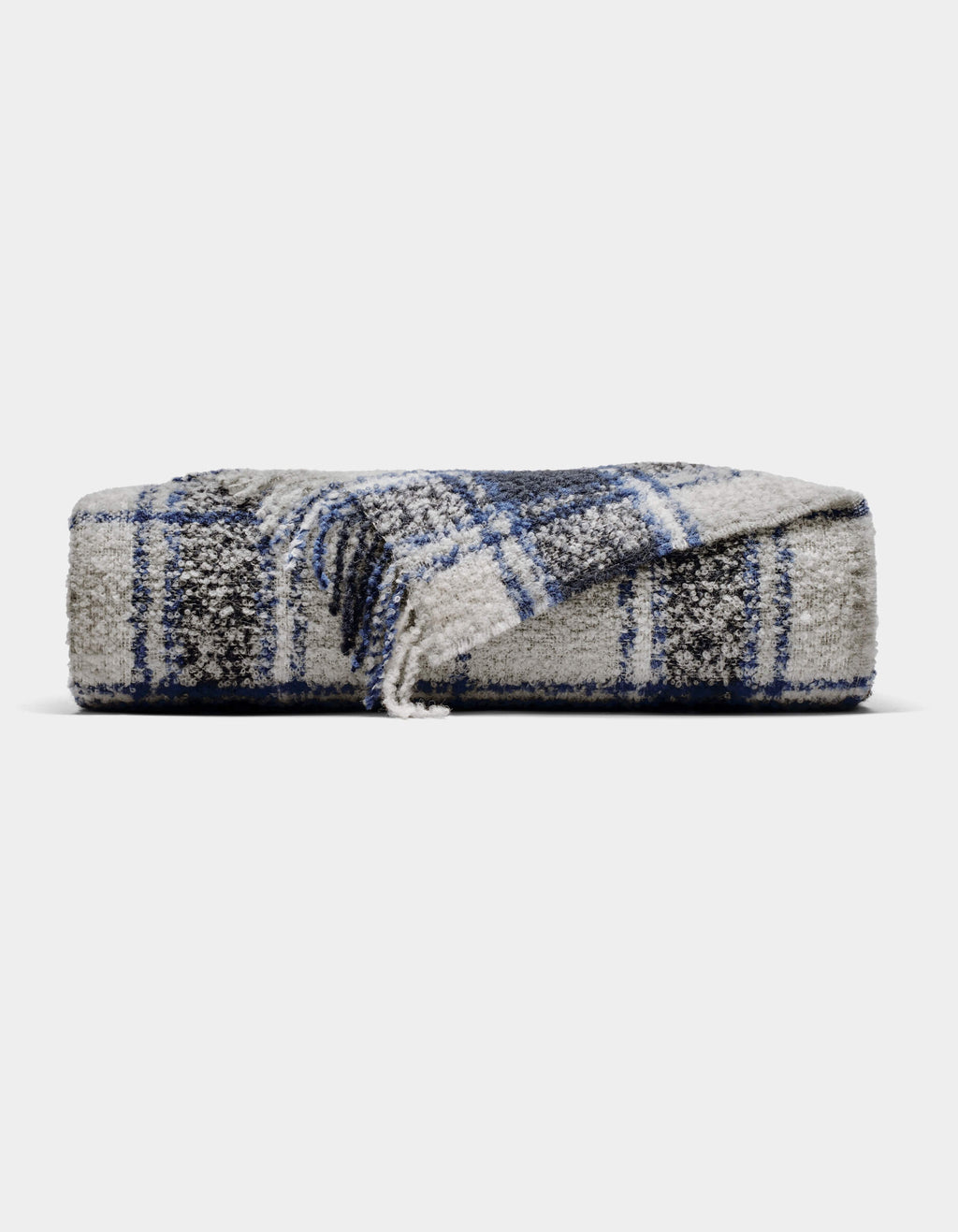 The Cozy Earth Alpaca Boucle Throw is a soft, gray blanket with a blue and white plaid pattern. Displayed against a plain background, one corner is partially unfolded to showcase its unique texture and design.|Color:Indigo Plaid