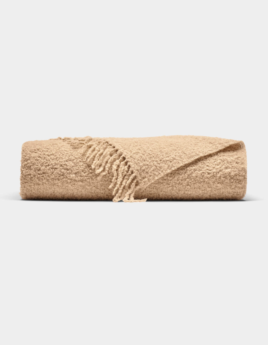 The Cozy Earth Alpaca Boucle Throw, featuring a textured surface and fringed edges in beige, is neatly folded and displayed against a plain white background.|Color:Sandalwood