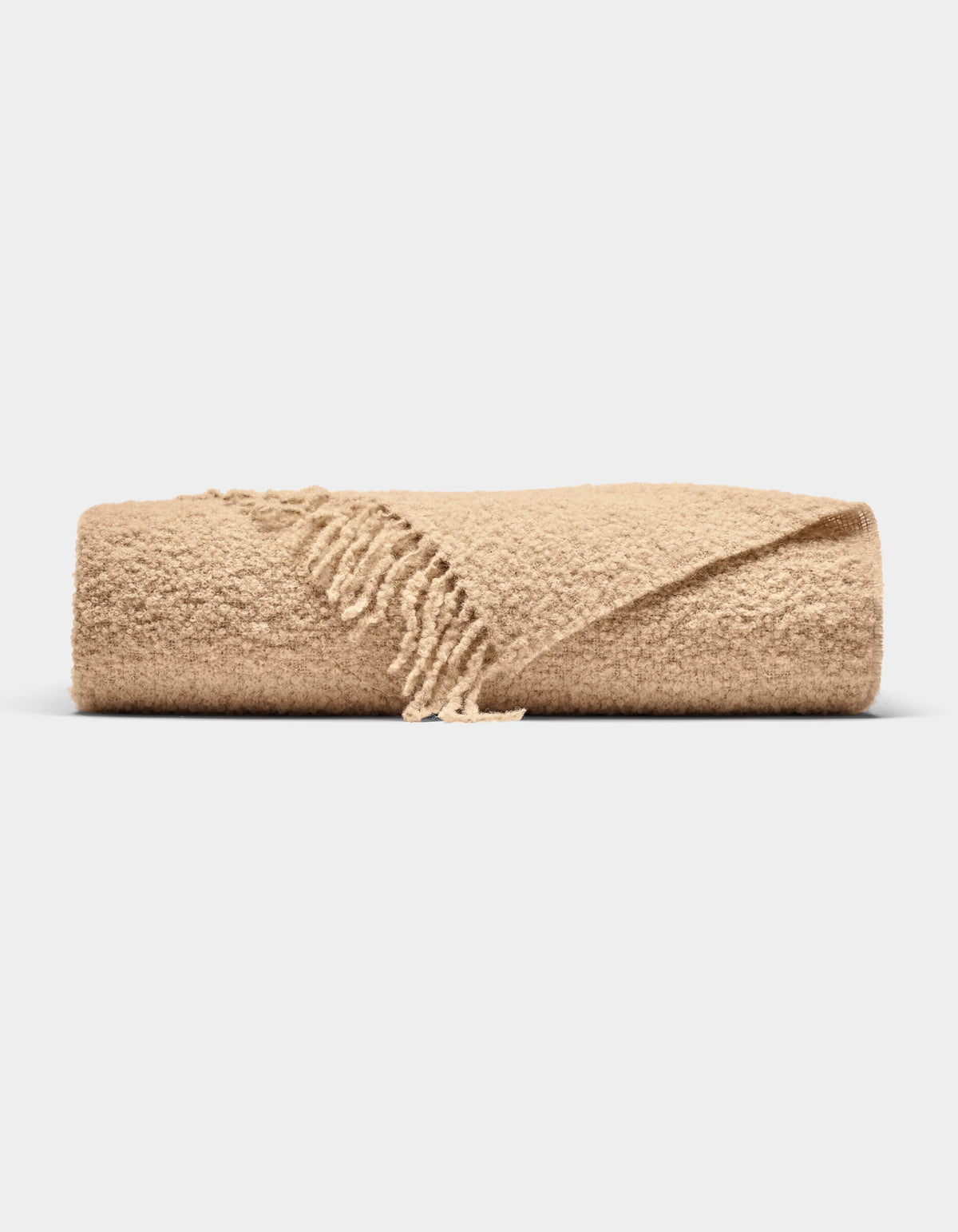 The Cozy Earth Alpaca Boucle Throw, featuring a textured surface and fringed edges in beige, is neatly folded and displayed against a plain white background.|Color:Sandalwood
