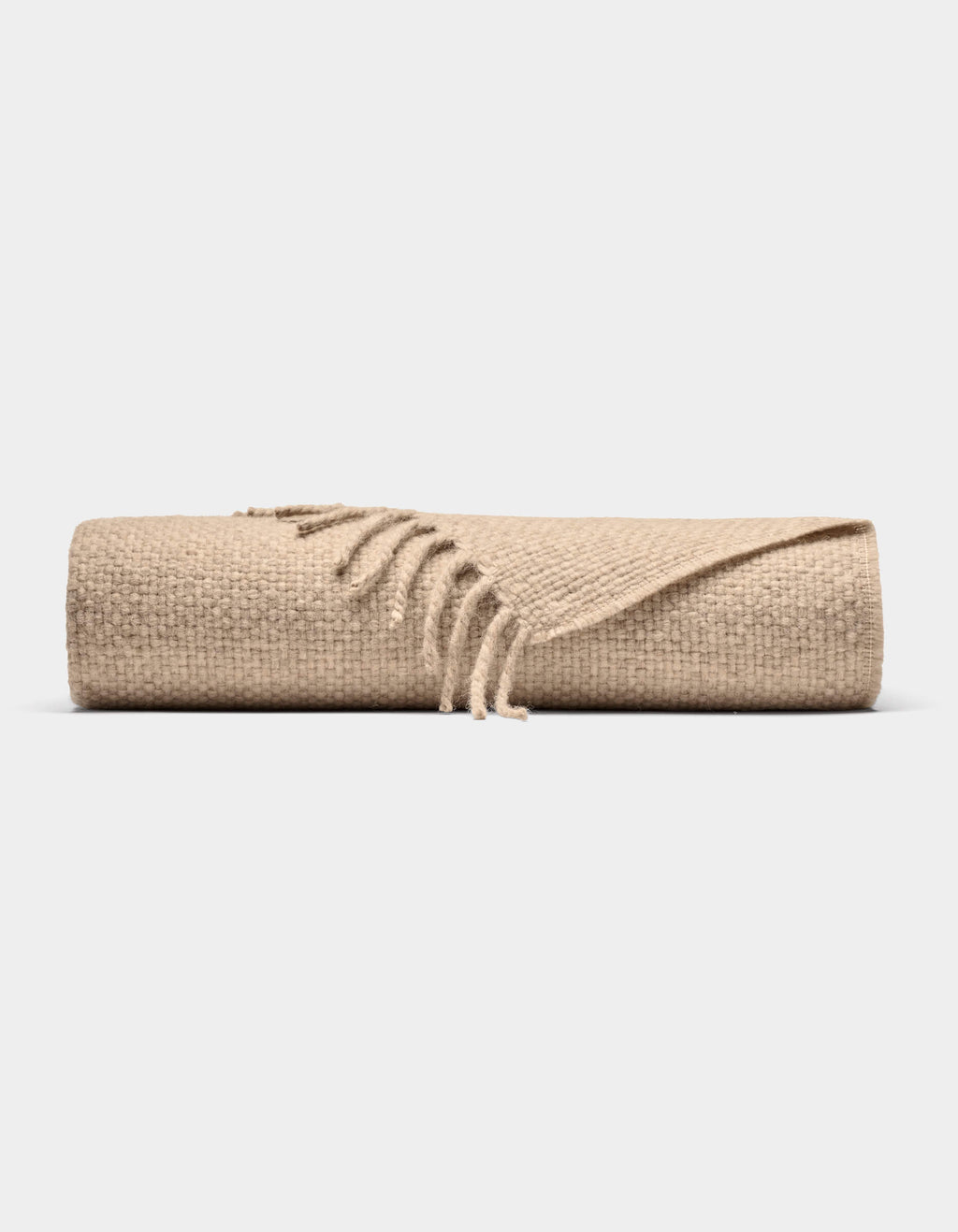 The Lucia Throw by Cozy Earth is a beige woven blanket with fringed edges, shown rolled up against a plain white background.|Color:Grain
