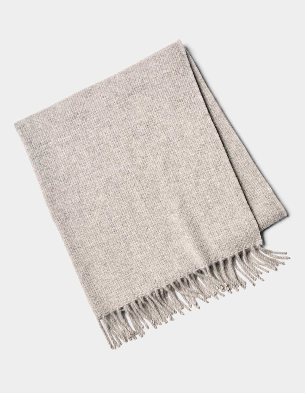 The Lucia Throw by Cozy Earth is a folded light gray woven blanket with fringe on one side, shown on a white background.|Color:Soft Grey