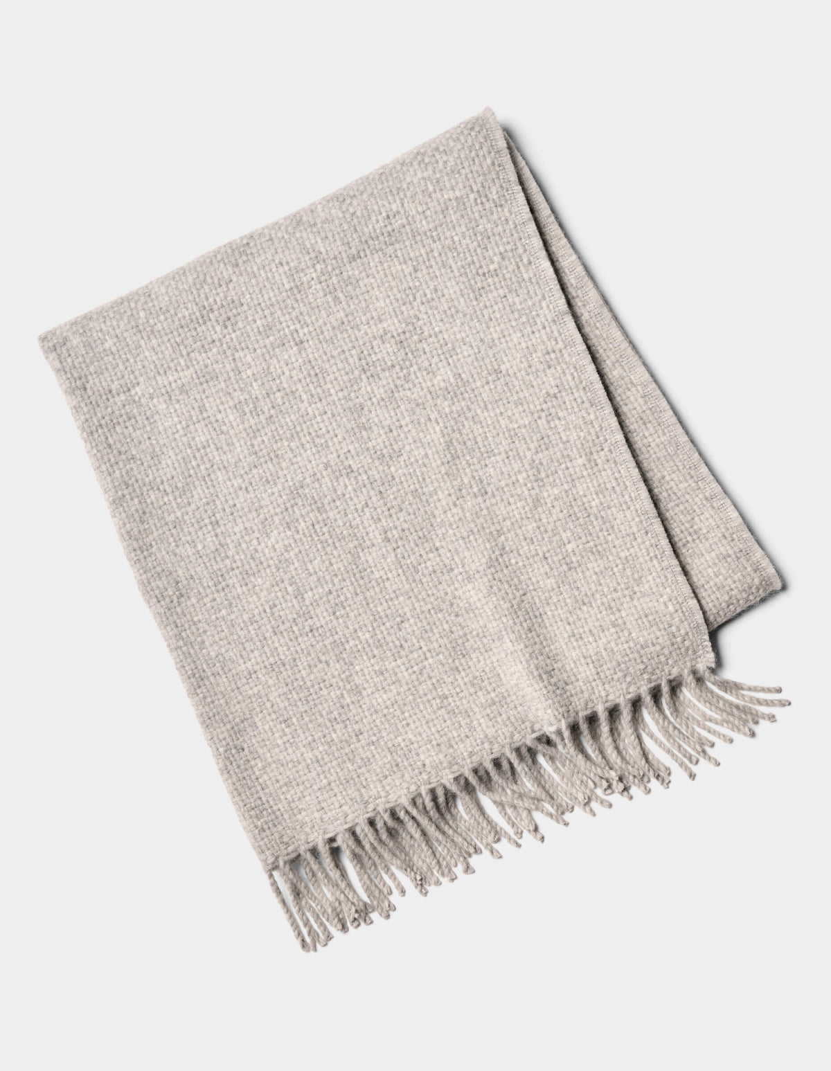 The Lucia Throw by Cozy Earth is a folded light gray woven blanket with fringe on one side, shown on a white background.|Color:Soft Grey