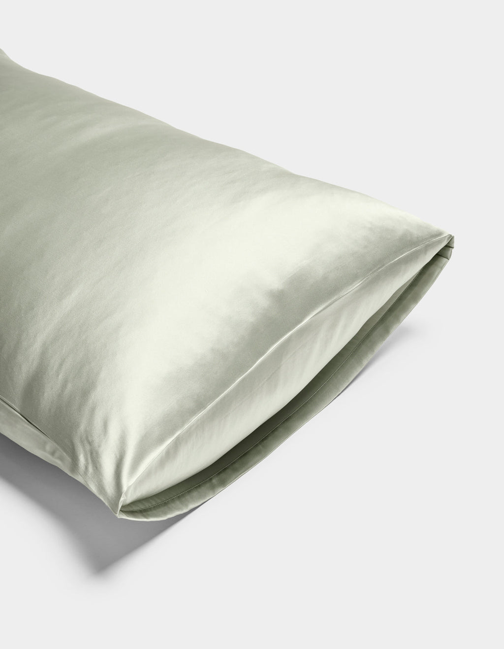A close-up of the Cozy Earth Silk Pillowcase in light green, featuring a smooth, shiny texture, displayed on a plain white background.|Color:Laurel