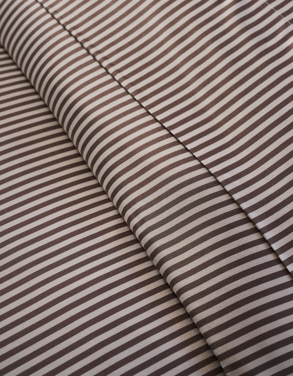 Close-up of Cozy Earth Bamboo Duvet Cover: brown and white stripes form diagonal lines, with two overlapping layers and subtle shadows at the fabric folds.|Color:Classic Stripe in Ebony