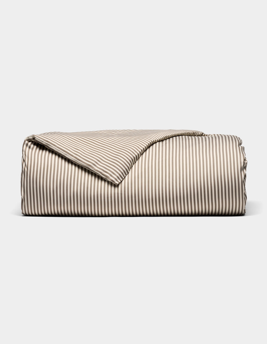 The Bamboo Duvet Cover by Cozy Earth, featuring beige and white stripes, is neatly folded and displayed against a plain white background.|Color:Classic Stripe in Ebony