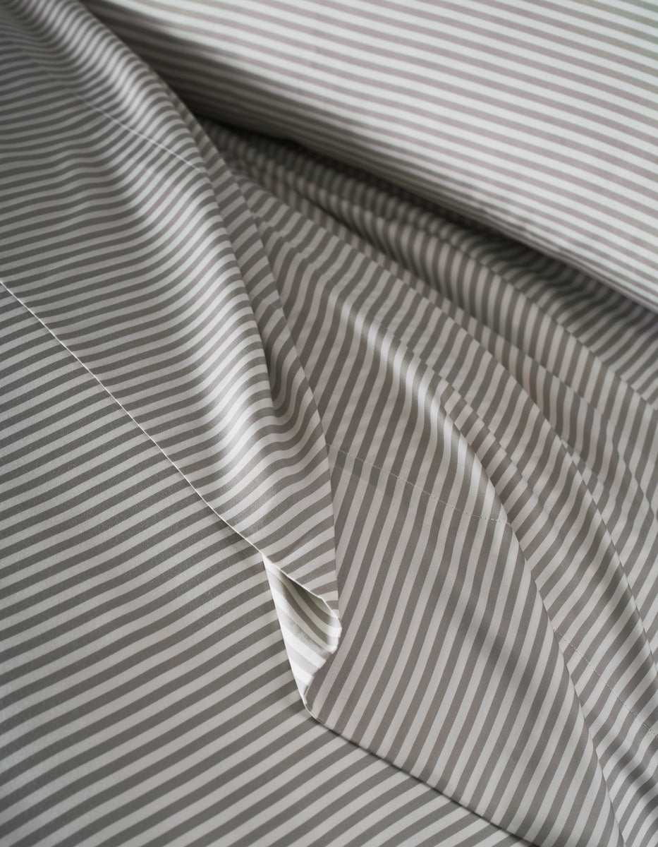Close-up of Cozy Earth's Bamboo Duvet Cover, neatly arranged with thin gray and white horizontal stripes. The top layer is slightly folded, showcasing the matching striped pattern.|Color:Classic Stripe in Laurel