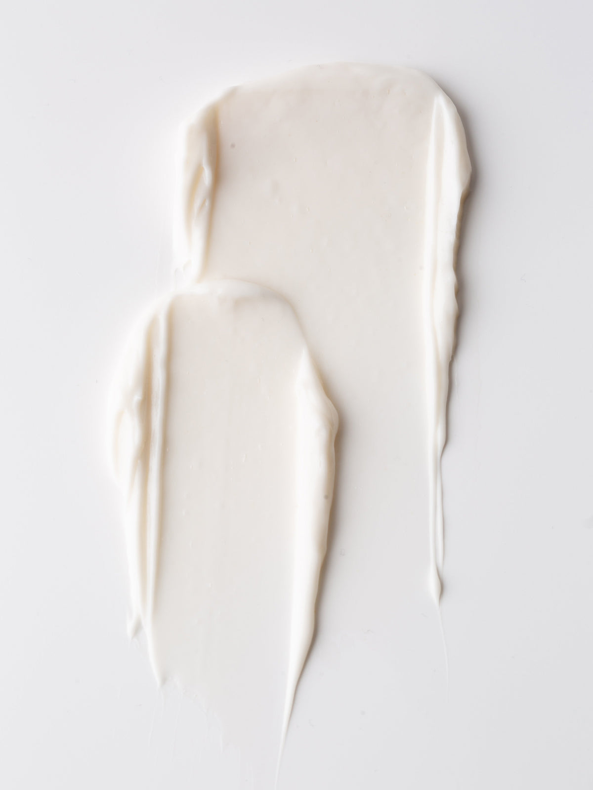 Two textured swatches of Cozy Earth Body Butter are spread on a clean, white surface. The Body Butter has a smooth, silky appearance with some visible ridges and lines from the spreading motion.|Size:Full Size