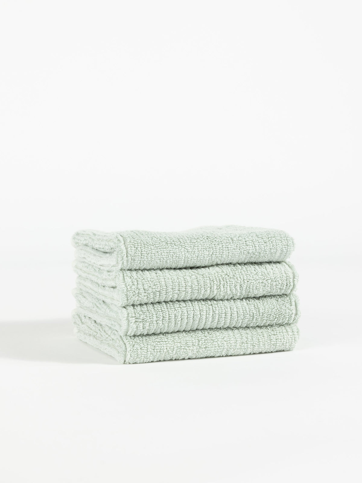 A neatly stacked pile of four light gray Ribbed Terry Washcloths from Cozy Earth is shown against a plain white background. The washcloths have a soft, fluffy texture, suggesting a comfortable and absorbent fabric. |Color:Laurel