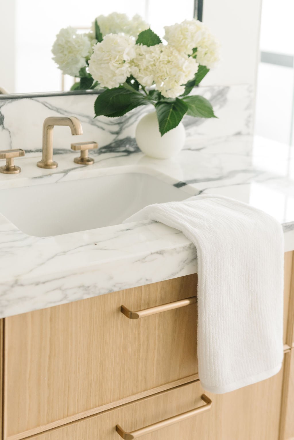 Ribbed Terry Hand Towel in the color White. Photo of Ribbed Terry Hand Towel taken with the Ribbed Terry Hand Towel resting on a bathroom sink. |Color: White