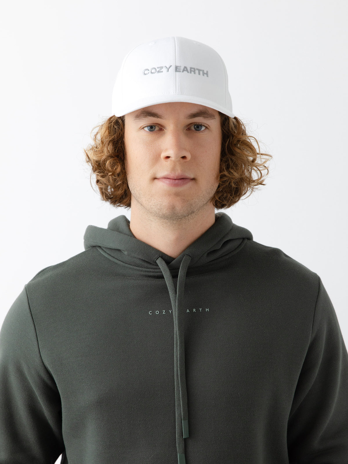 A man wearing a White cap with 'COZY EARTH' text on a white background |Color:White/Stone