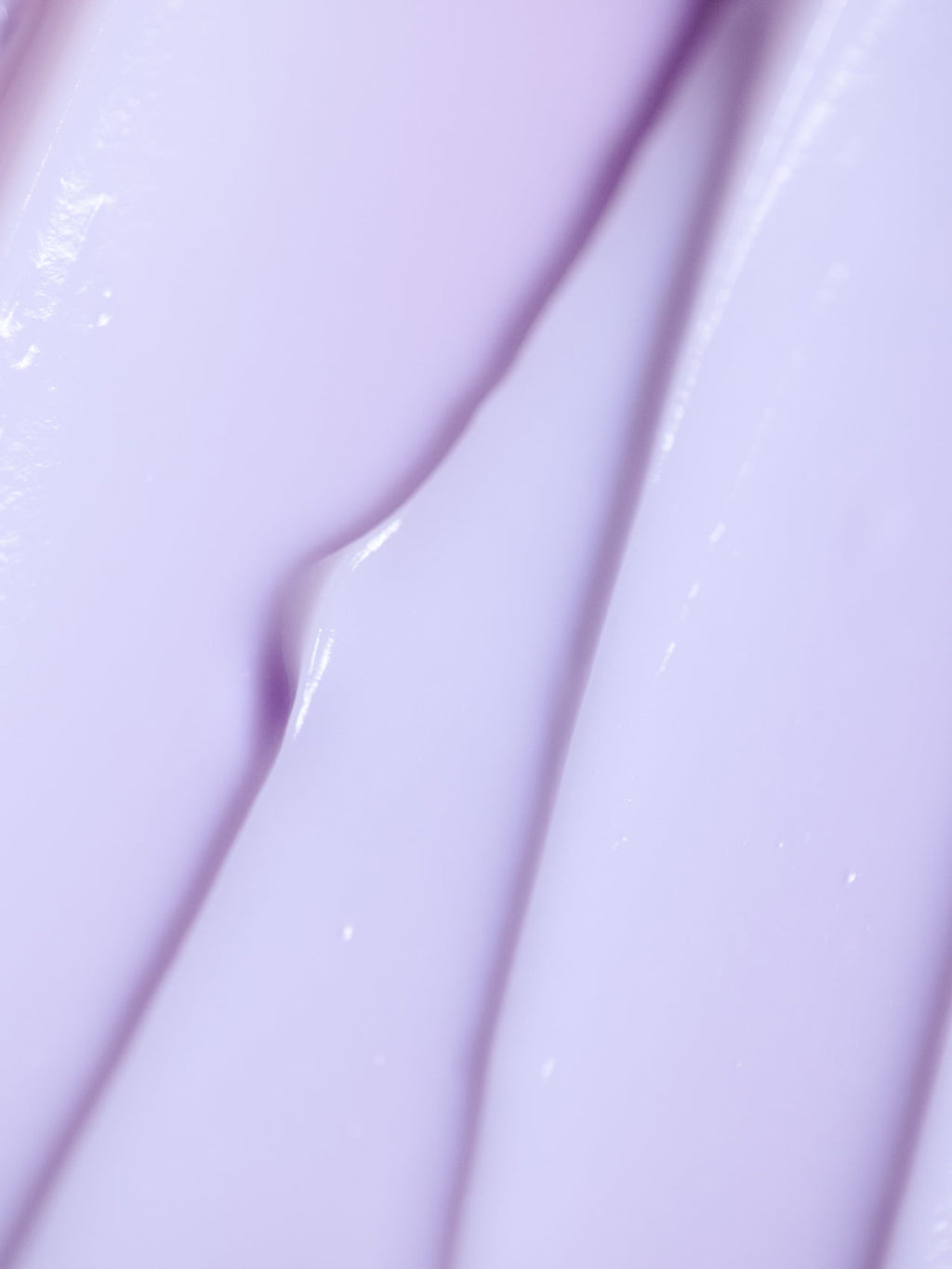 Close-up of Cozy Earth's Night Cream, showcasing its smooth purple texture with light reflections forming an abstract pattern of creamy ridges and folds. |Size:Full Size