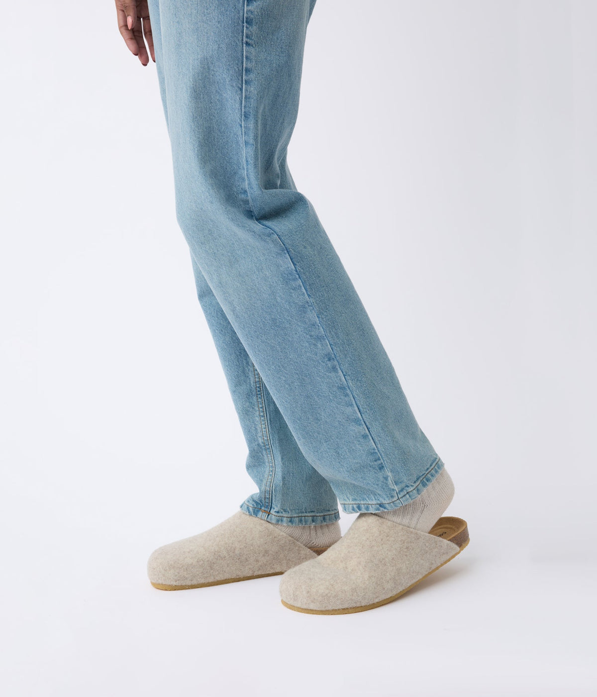 A person wearing light blue jeans and the Cozy Earth Lakehouse Clog with cream-colored socks stands against a plain white background, showing only the lower half of their body. |Color:Oat