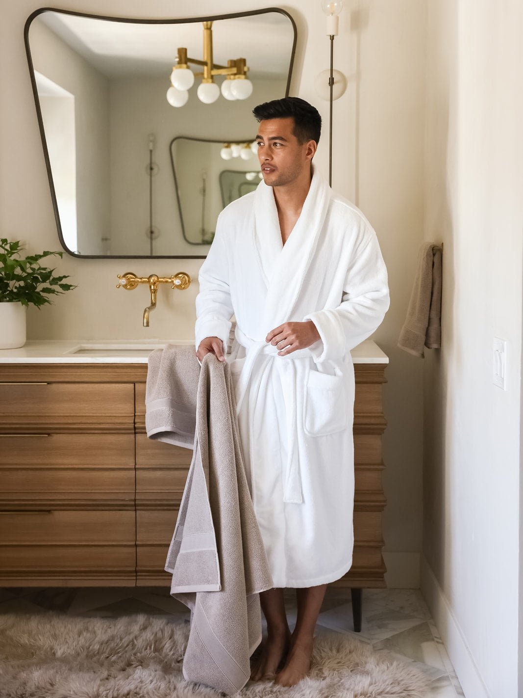 Man in white robe holding sand luxe bath towel |Color:Sand