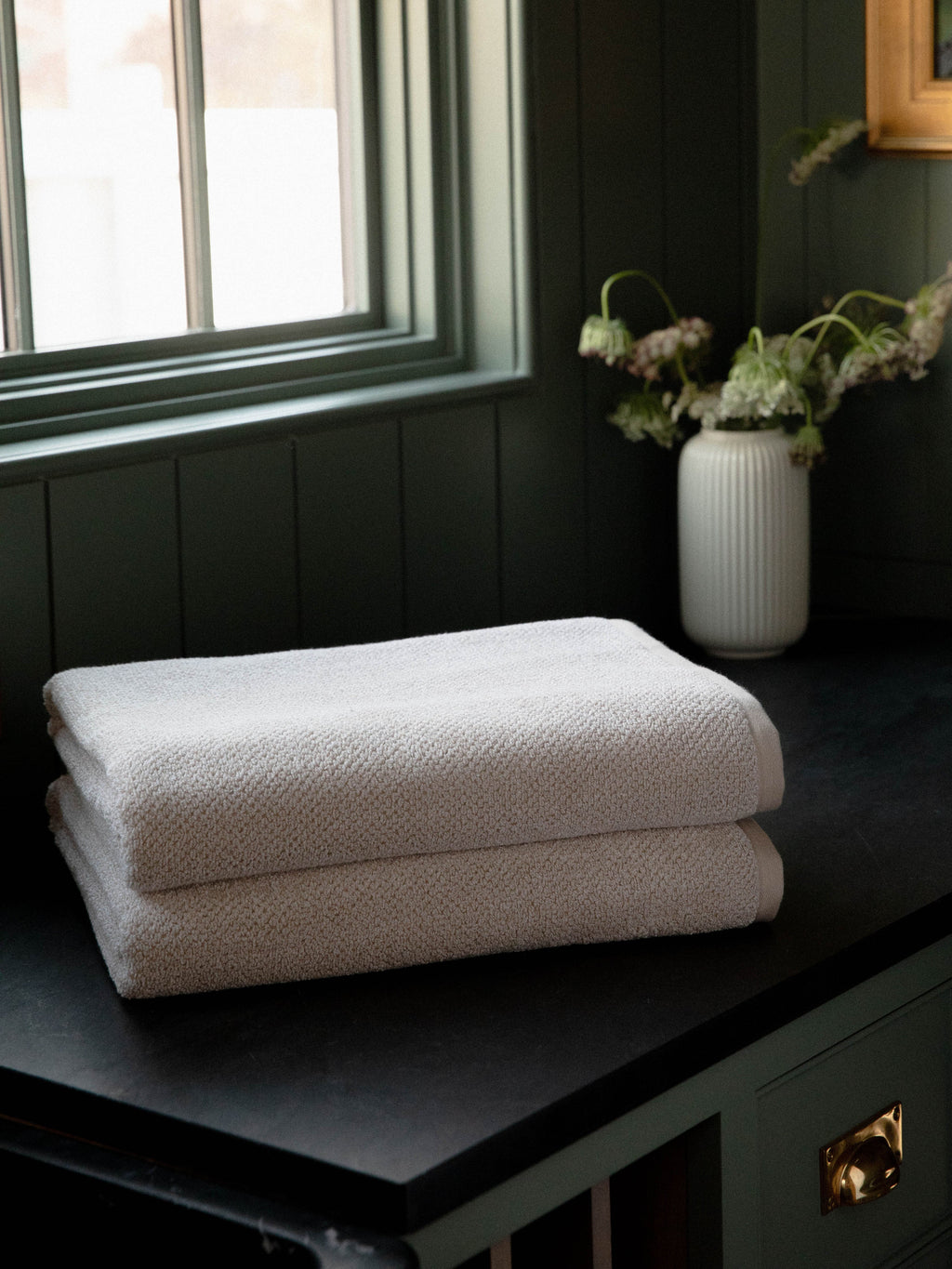 Nantucket Bath Sheets in the color Heathered Sand. Photo of Nantucket Bath Sheets taken with the bath Sheets resting on a countertop in a bathroom. |Color: Heathered Sand