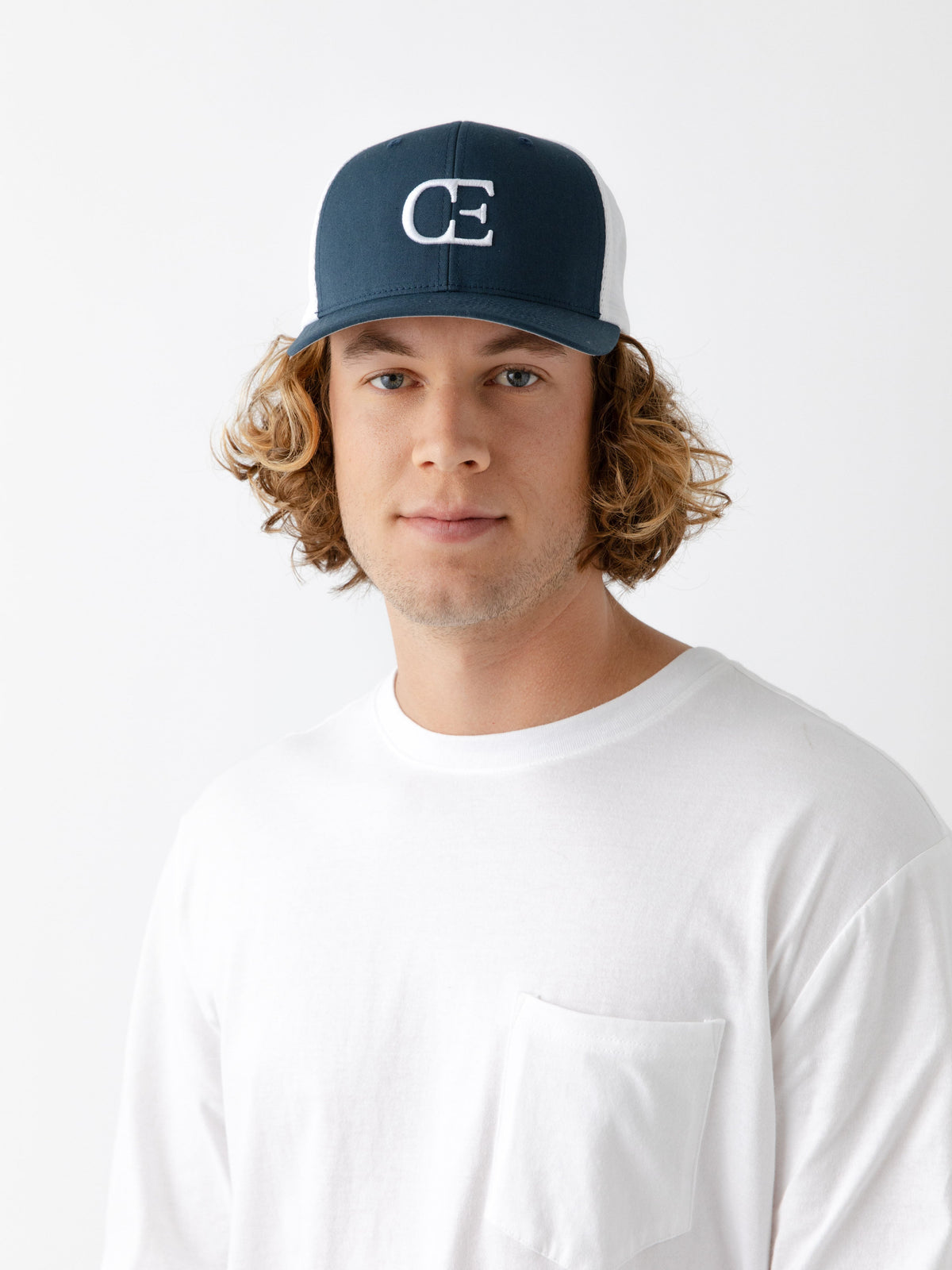 Man wearing a Navy and white cap with a CE logo on a light gray background |Color:Navy/White