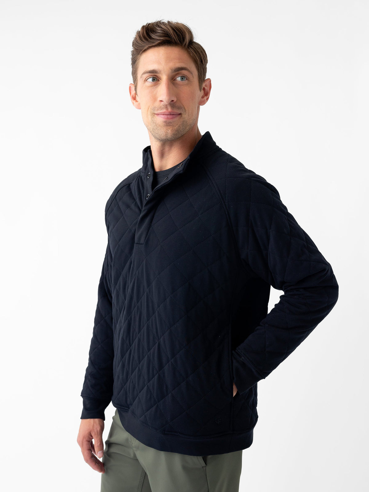 A person wearing a Cozy Earth Men's Ultra-Soft Bamboo Quilted Snap Pullover stands against a white background. The individual has short brown hair and a focused expression, with their right hand resting on their hip and looking slightly to the side. |Color:Black