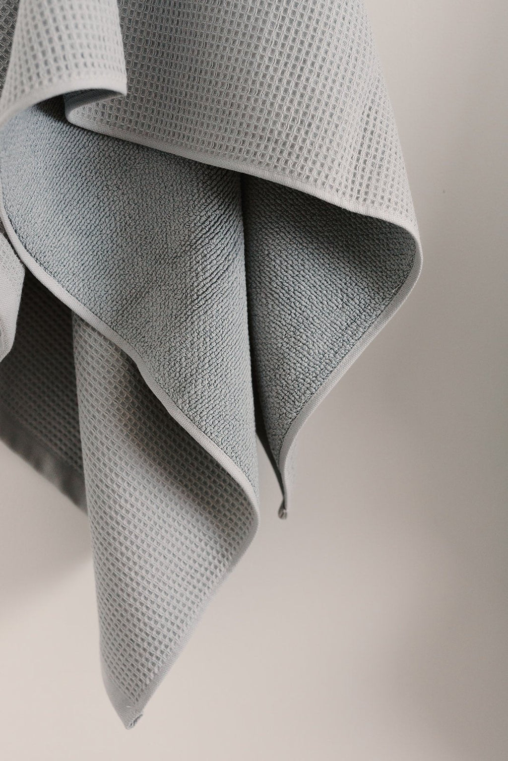 Waffle Bath Towel in the color Harbor Mist. Photo of Harbor Mist Waffle Bath Towel taken hanging from a towel hook in a white bathroom. |Color: Harbor Mist