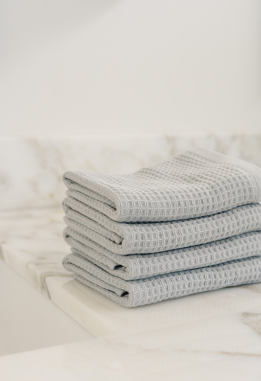 Harbor Mist Waffle Wash Cloths neatly folded. The photo was taken with the cloths resting on a white marble sink. |Color:Harbor Mist