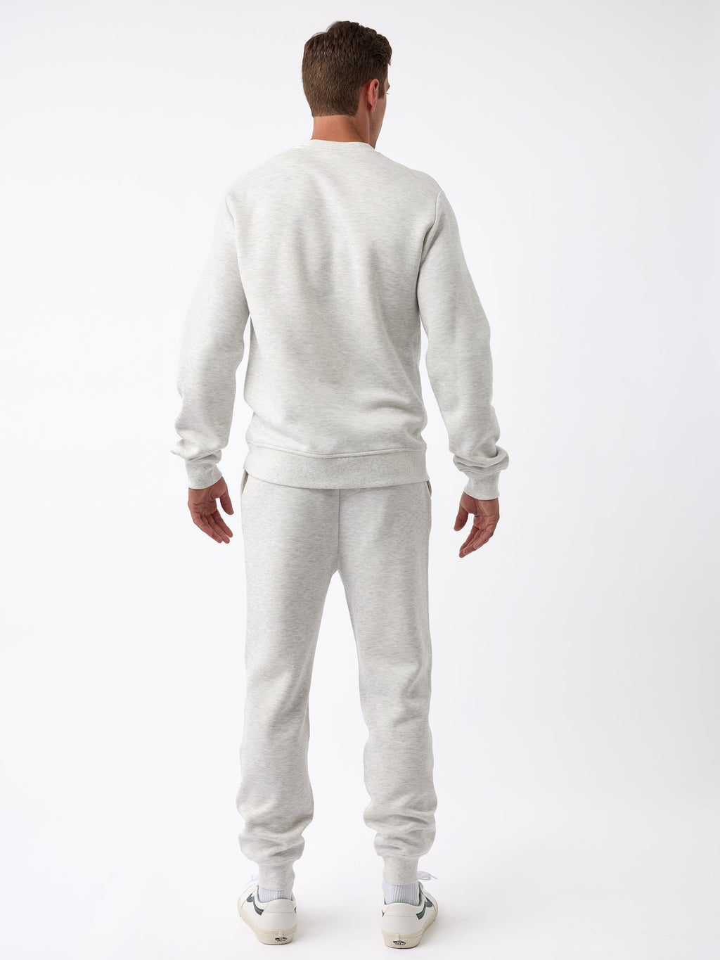 A person is wearing the Men's CityScape Jogger from Cozy Earth in a light gray color, paired with white sneakers, and is facing away from the camera against a plain white background. |Color:Heather Grey