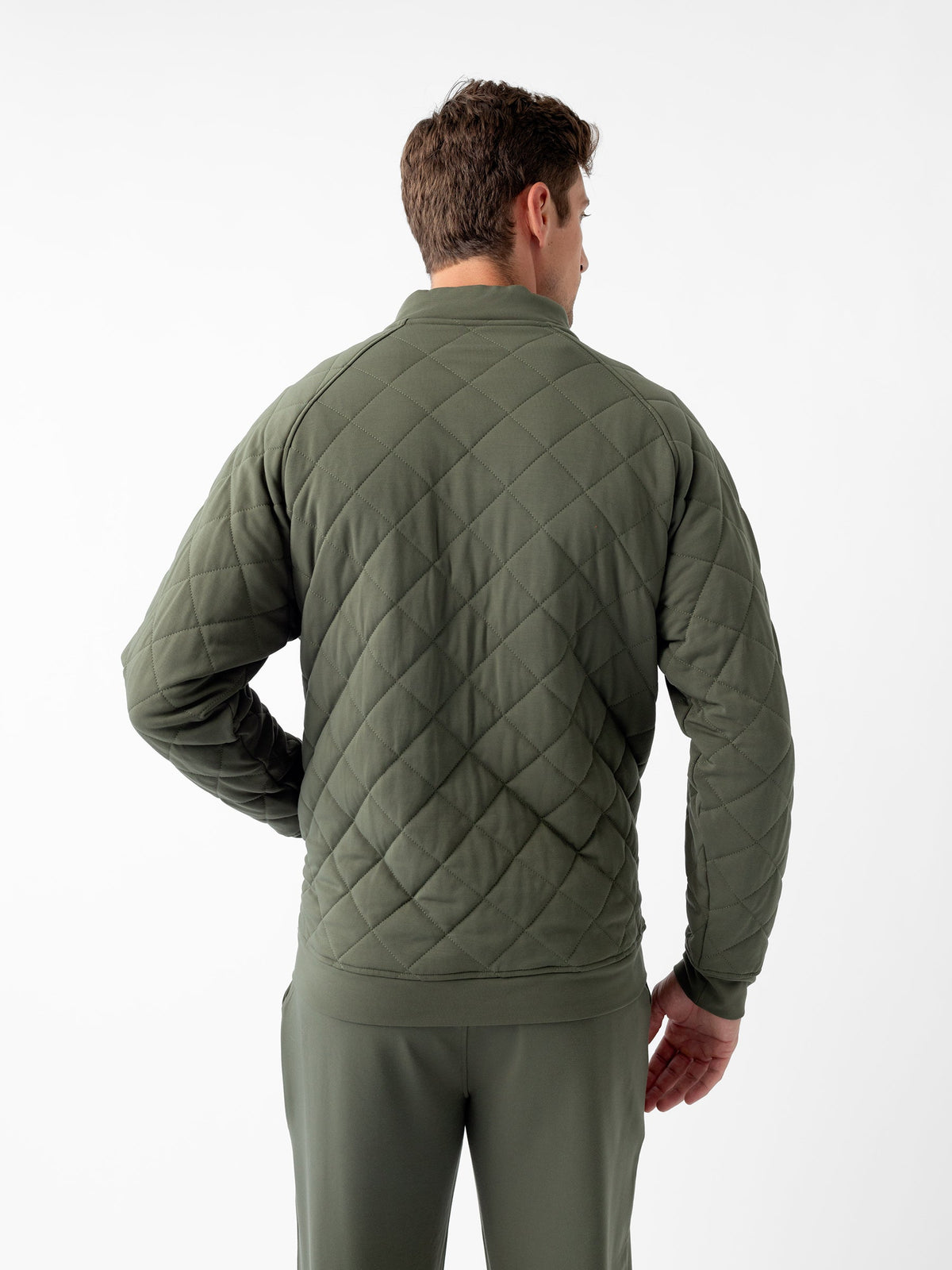 A man wearing a Cozy Earth Men's Ultra-Soft Bamboo Quilted Snap Pullover in olive green and matching pants is standing with his back facing the camera against a plain white background. The pullover features a diamond pattern and has a high collar. His short hair is styled neatly. |Color:Olive