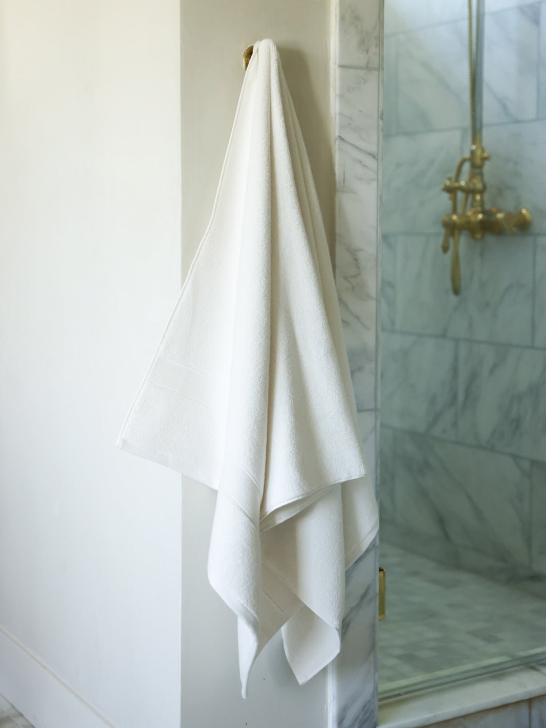 Seashell luxe bath sheet hanging next to shower |Color:Seashell