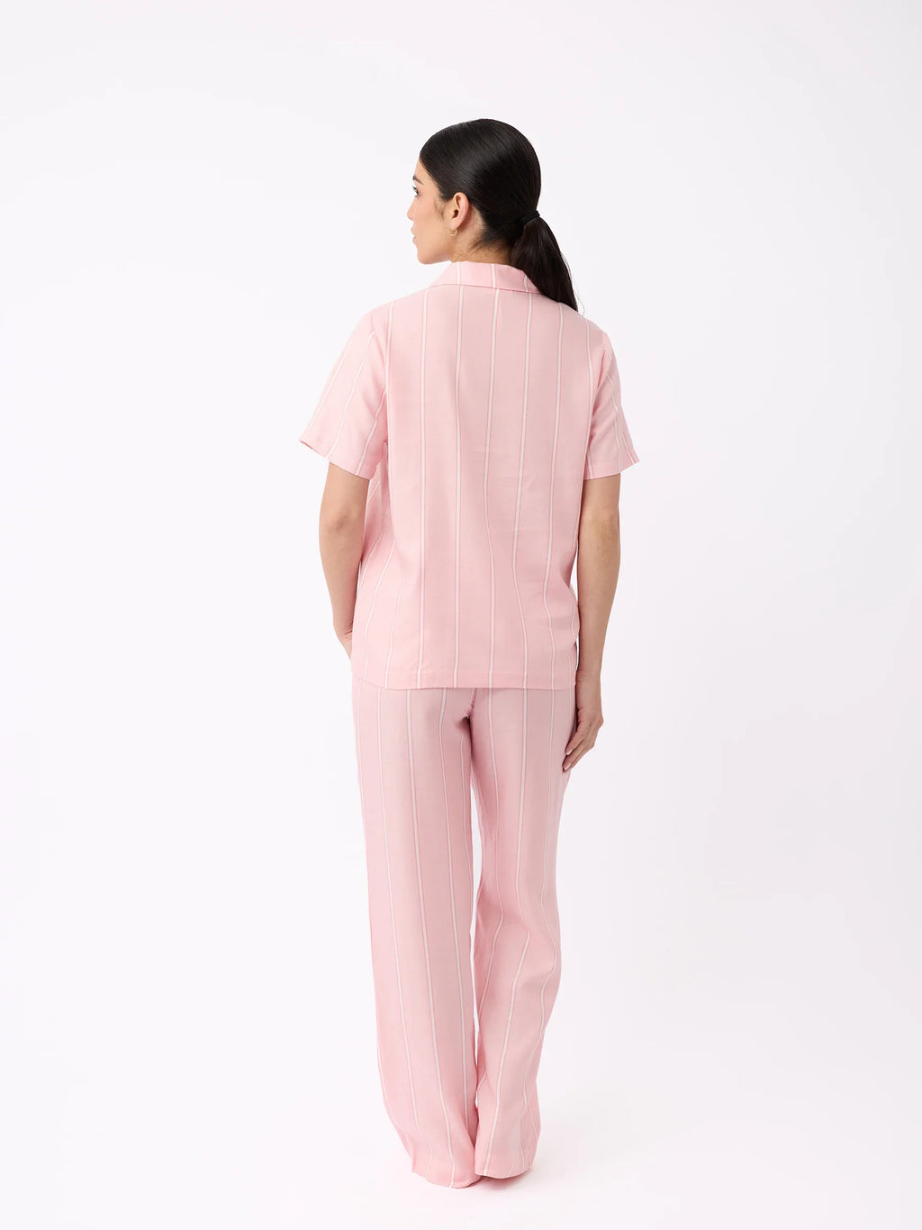 A woman with long dark hair, back to the camera, wears Cozy Earth's pink short-sleeve top and Women's Soft Woven Pajama Pant with subtle vertical stripes against a plain white background. |Color:Sweetheart Stripe