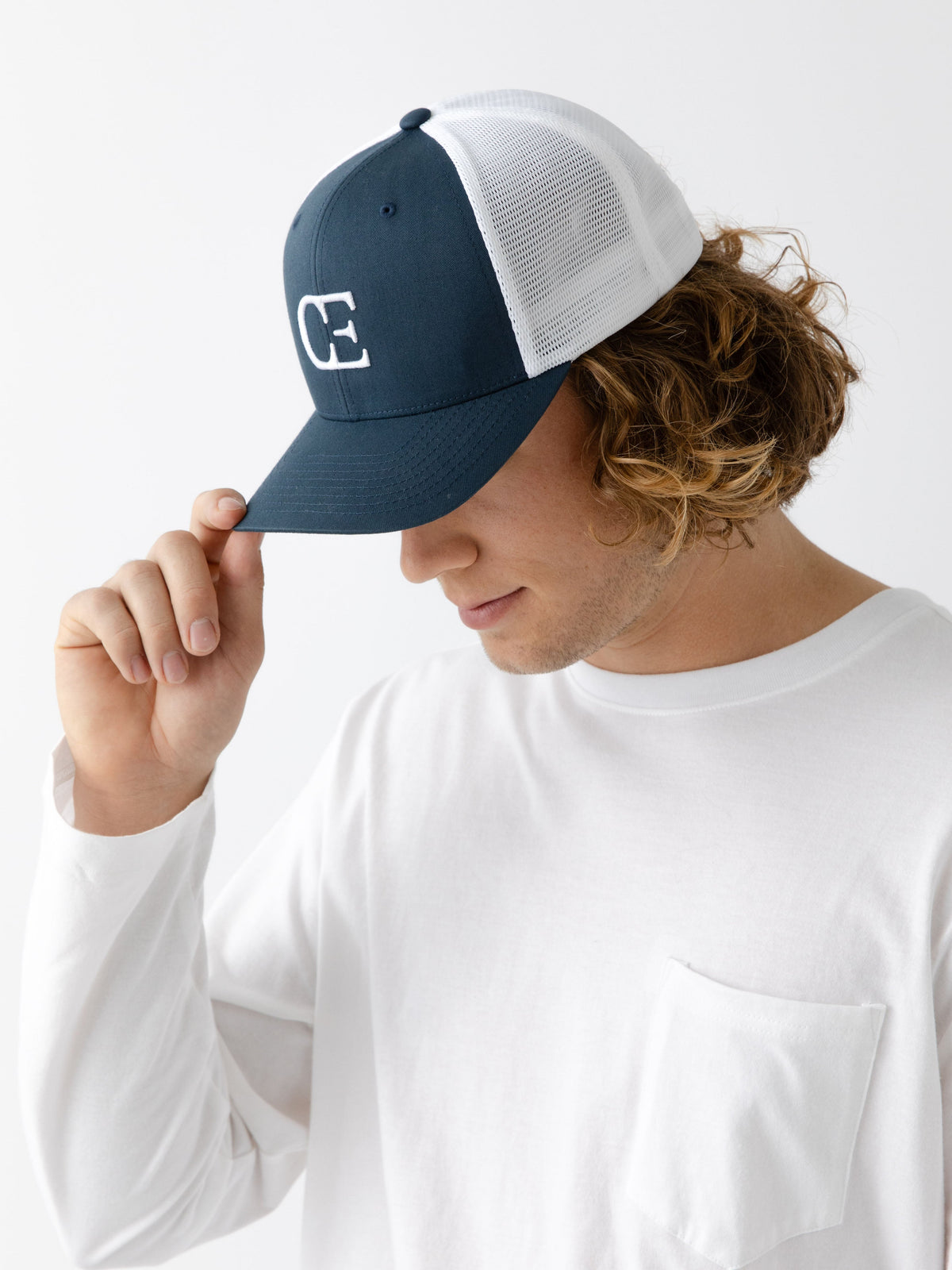 Man wearing a Navy and white cap with a CE logo on a light gray background |Color:Navy/White