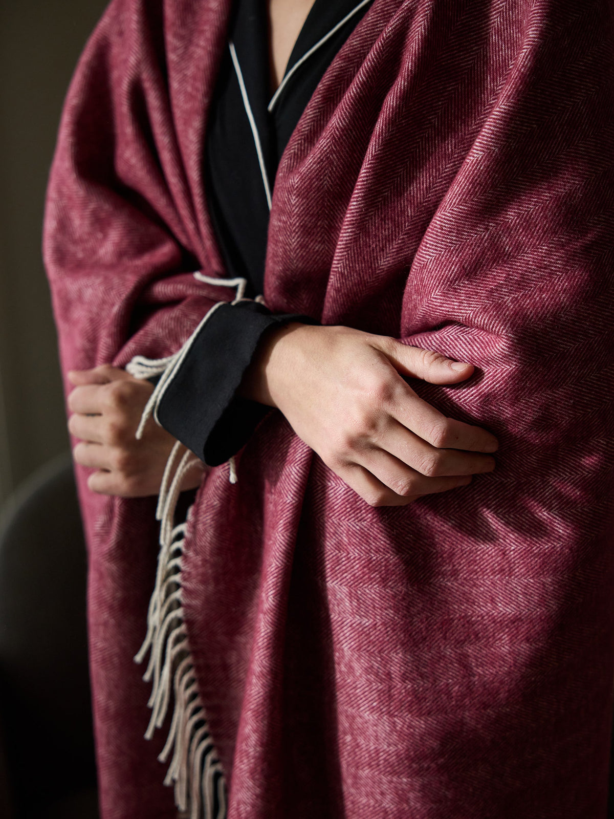 Close up of woman with berry herringbone tassel throw wrapped around her |Color:Berry