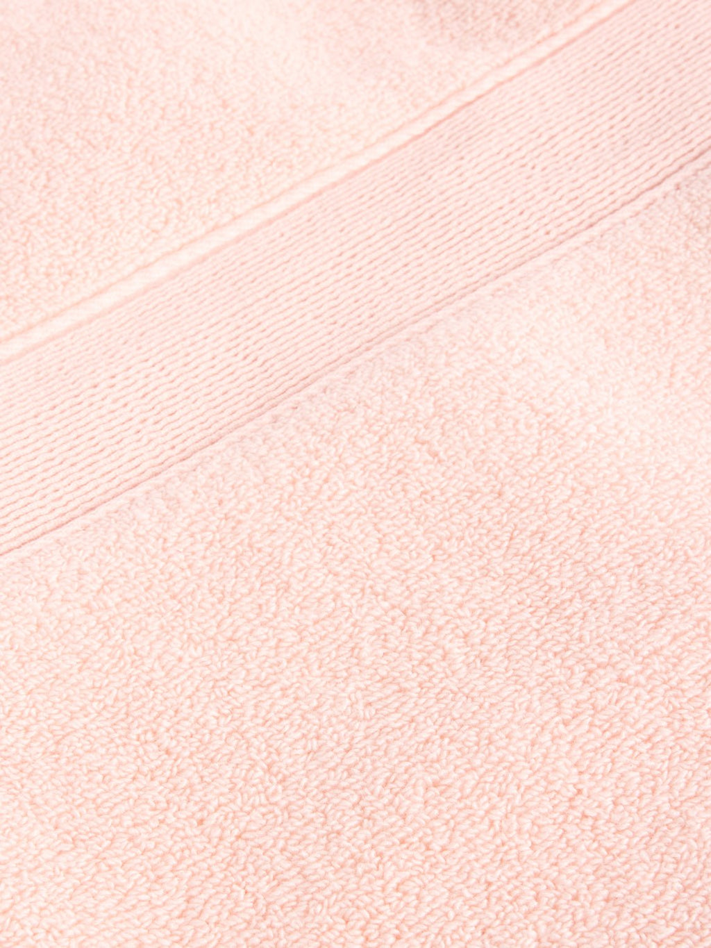Close-up of a Luxe Bath Towel by Cozy Earth in light pink, featuring a fluffy texture with a horizontal band design near the top edge. |Color:Blossom