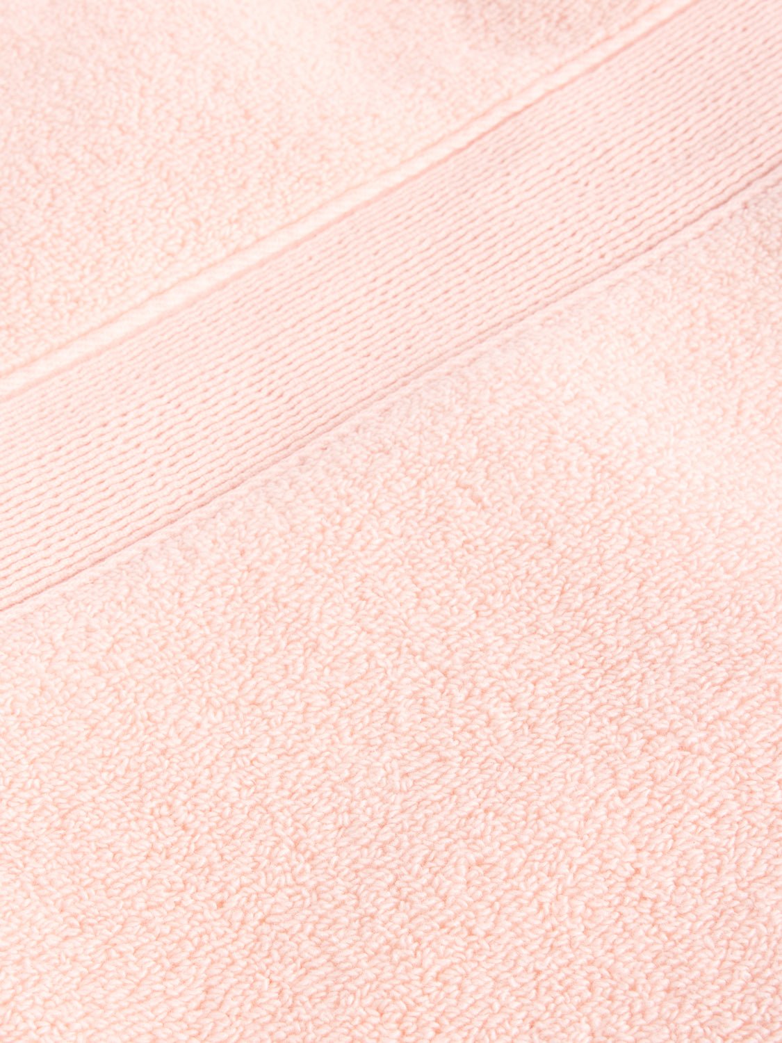 Close-up of a Luxe Bath Towel by Cozy Earth in light pink, featuring a fluffy texture with a horizontal band design near the top edge. |Color:Blossom