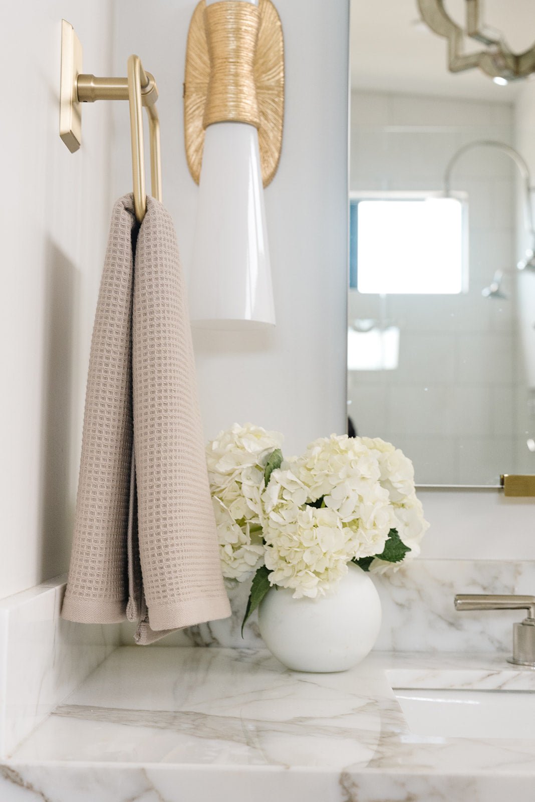 Sand Waffle Hand Towel hanging from a gold towel ring. The photo was taken at a white marble bathroom sink. |Color:Sand