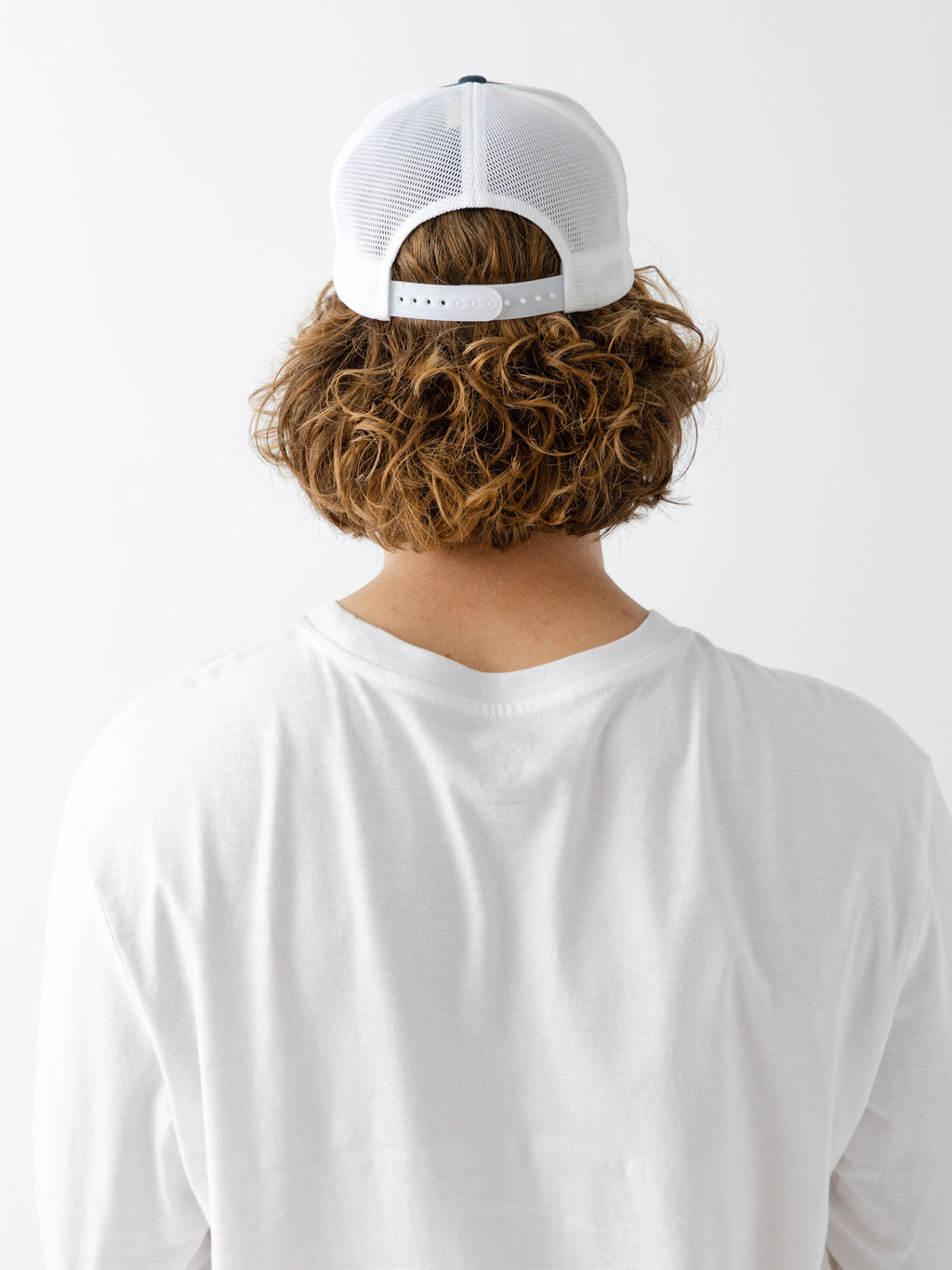 Man facing backwards wearing a Navy and white cap with a CE logo on a light gray background |Color:Navy/White