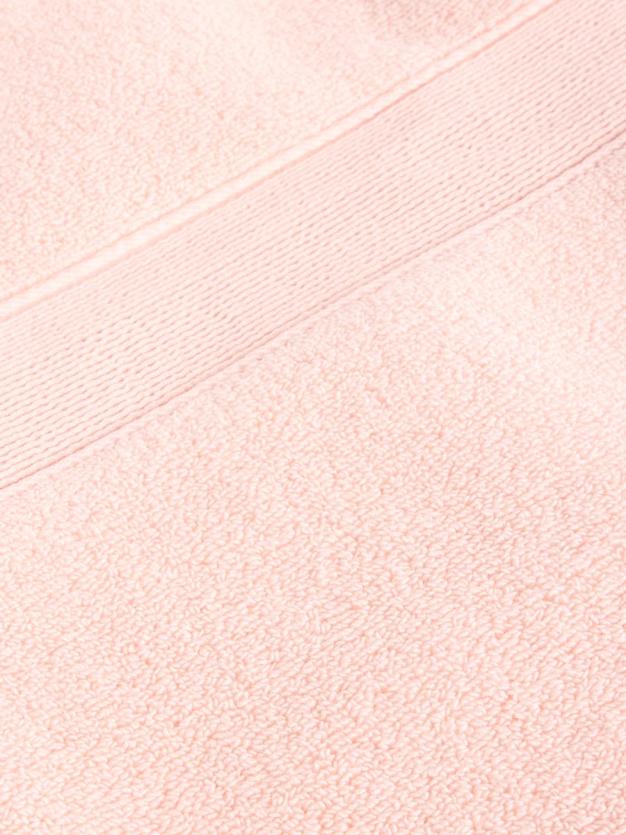 Close-up of Cozy Earth's Luxe Bath Towel Set, featuring a peach-colored, textured weave with a decorative horizontal band. The plush and absorbent fabric is ideal for personal or home use. |Color:Blossom