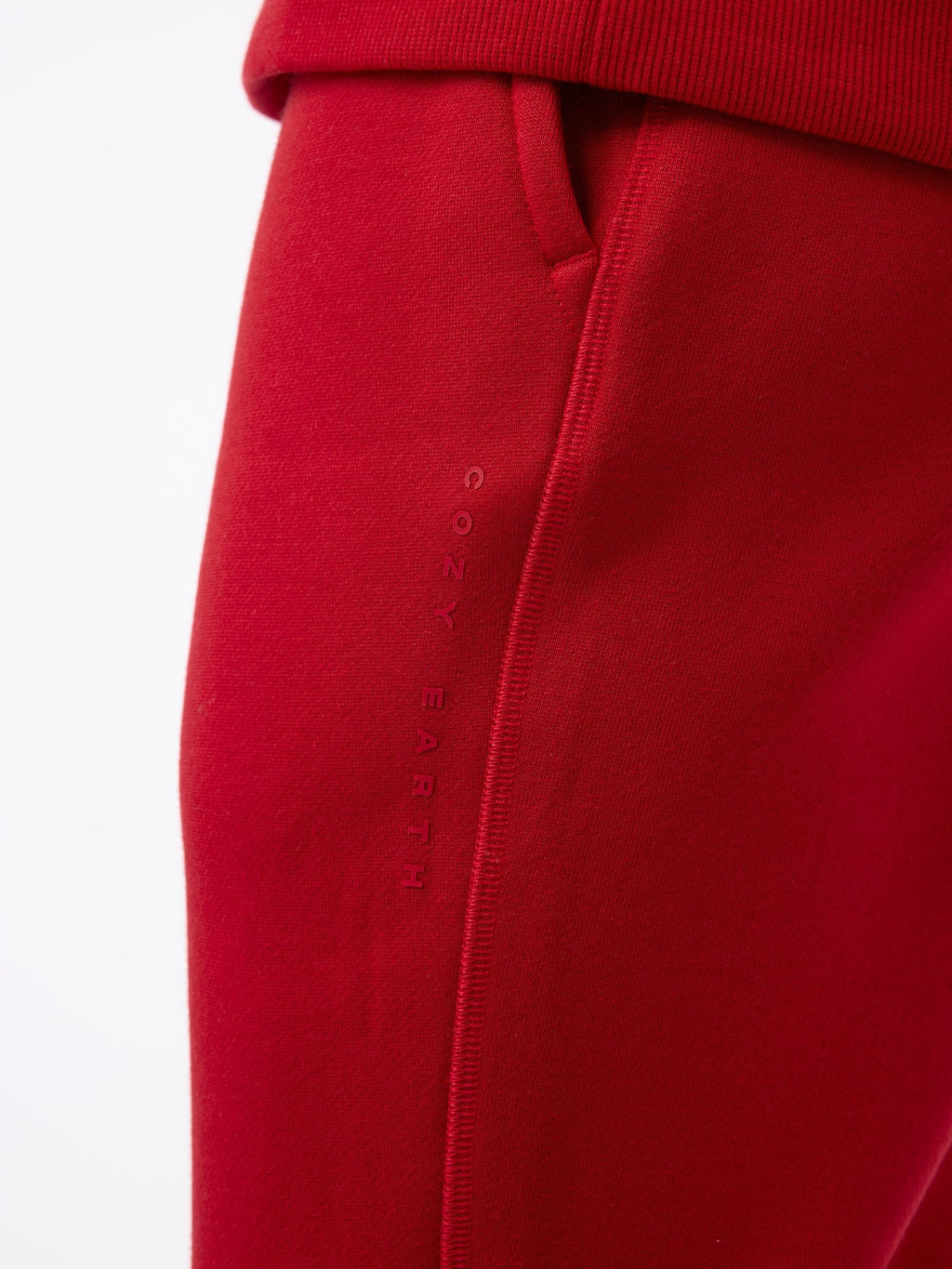 Close-up of the Men's CityScape Jogger in red, featuring a side pocket with "Cozy Earth" embroidered vertically. The texture appears soft and smooth, highlighting the comfortable fabric. The focus is on the stitching and fabric detail. |Color:Crimson