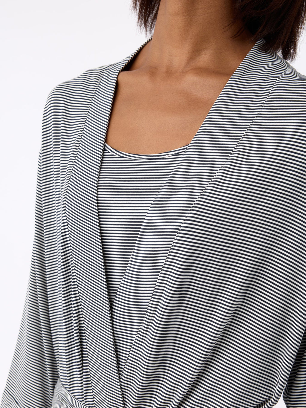 A person models the Cozy Earth Women's Bamboo Stretch-Knit Kimono Robe in black and white stripes with a V-neck and draped, overlapping front. Their hair is shoulder-length against a plain white background.|Color:Eclipse Mini Stripe