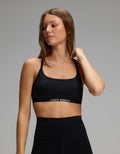 A person wearing a black, scoop-neck Women’s Balance Bra by Cozy Earth with a branded elastic band.|Color:Jet Black