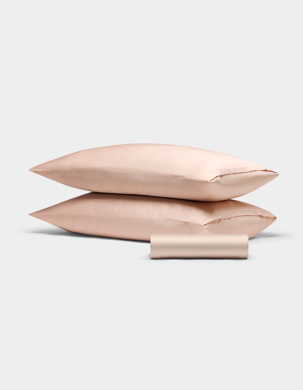 The Cozy Earth Bamboo Bedding Basic Bundle features two light pink satin pillowcases stacked, with a matching satin sleep mask in front, all set against a plain white background.|Color:Peony
