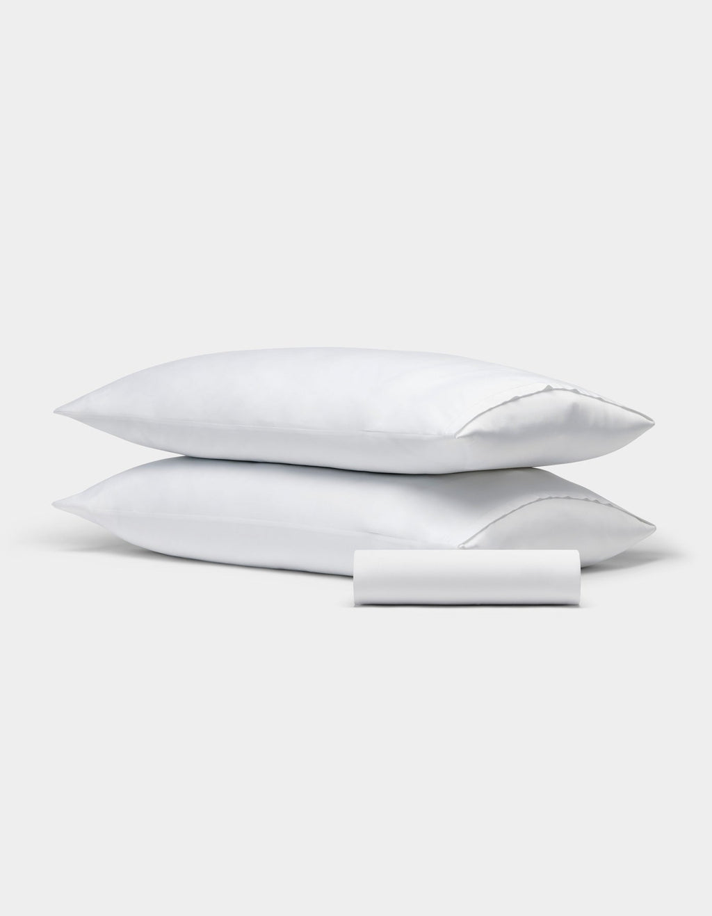 Two white rectangular pillows from the Cozy Earth Bamboo Bedding Basic Bundle are stacked, with a matching small cylindrical bolster in front, all set against a plain light gray background.|Color:White
