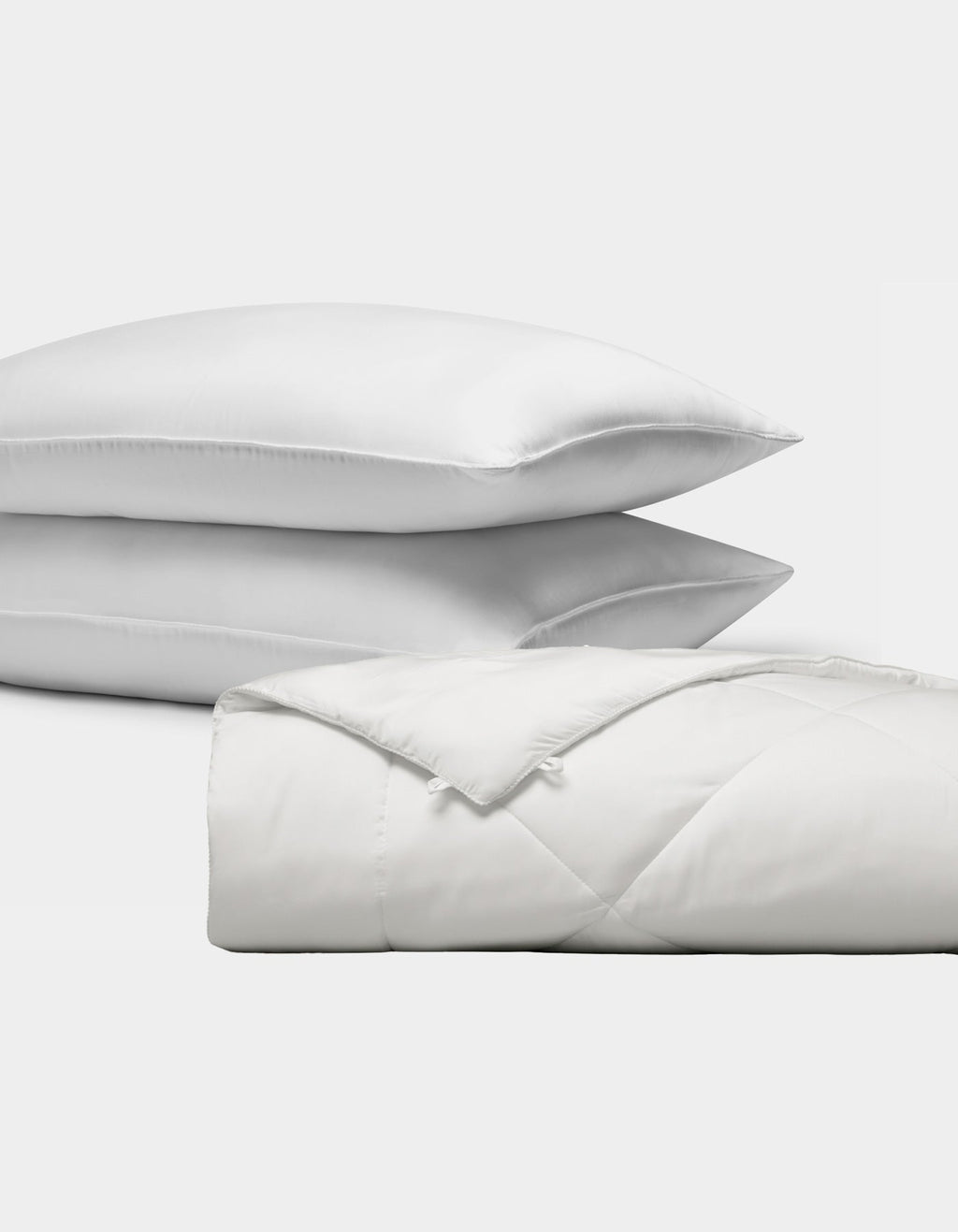 The Bamboo Insert Bundle by Cozy Earth features two stacked white pillows and a folded, quilted white comforter, all displayed against a plain white background.|Filling:Extra