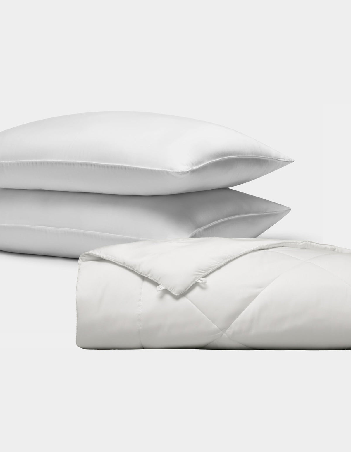The Bamboo Insert Bundle by Cozy Earth features two stacked white pillows and a folded, quilted white comforter, all displayed against a plain white background.|Filling:Extra