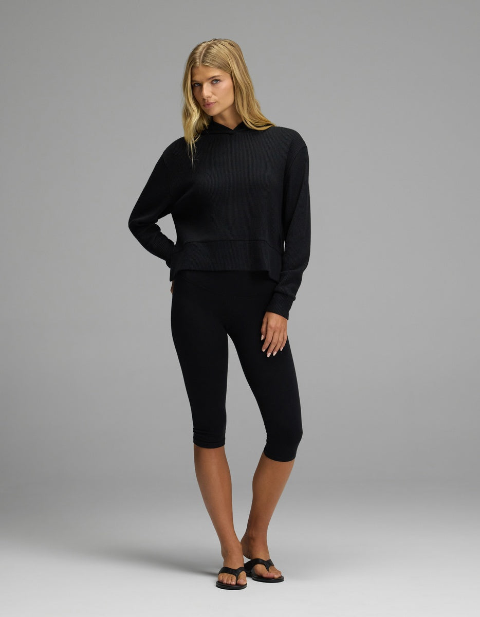 A woman wearing a black Women’s Blake Waffle Hoodie and black cropped leggings.|Color:Jet Black