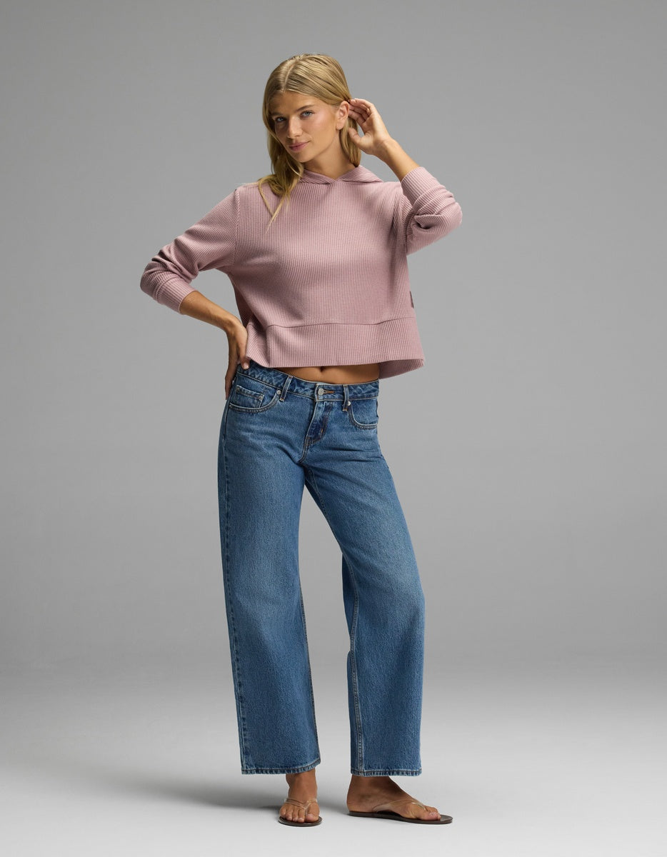 A woman wearing a mauve long-sleeved Cozy Earth Women’s Blake Waffle Hoodie and wide-leg blue jeans.|Color:Viola