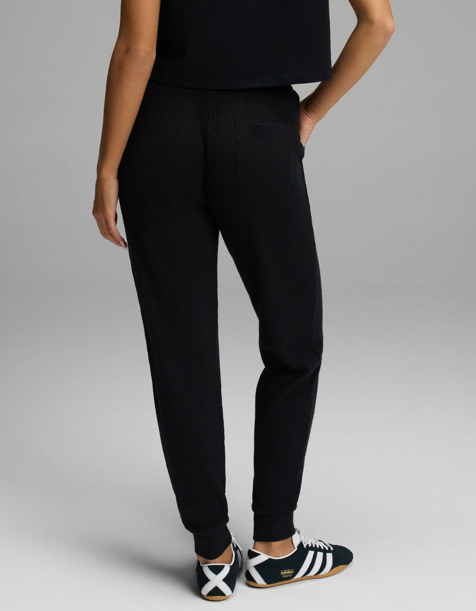 Back view of a person wearing black Women’s Blake Waffle Jogger pants with ribbed cuffs and sneakers.|Color:Jet Black