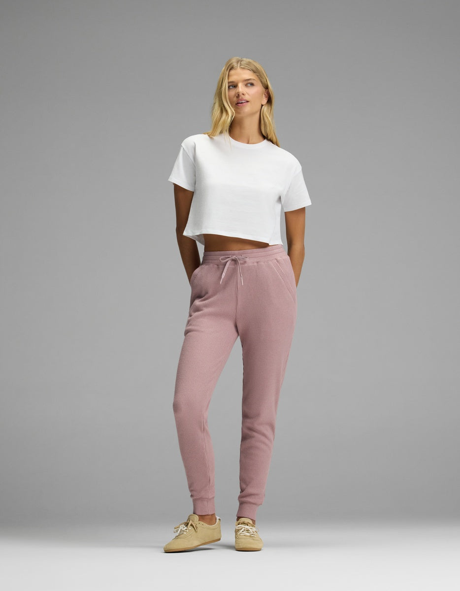 A woman wearing a white cropped t-shirt and mauve Women’s Blake Waffle Jogger pants with a drawstring waist.|Color:Viola